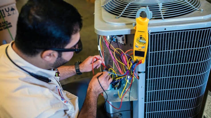 Technician checking air conditioner wiring with a clamp meter