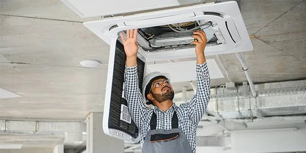 Technician working on a ceiling-mounted air conditioning unit